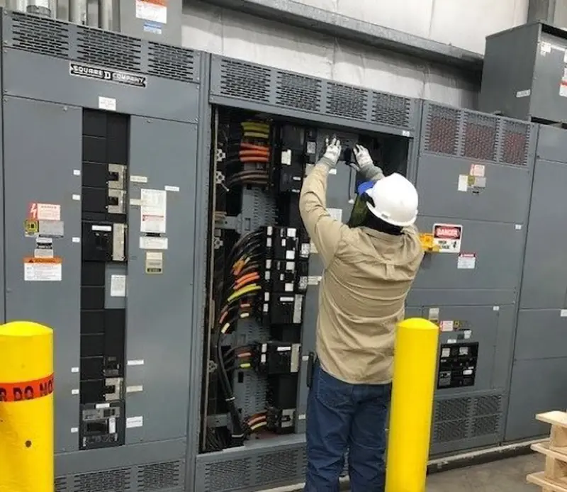 worker in safety gear performing test on electrical system